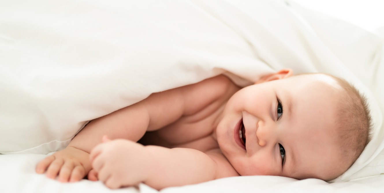 happy cute baby lying on a white sheet