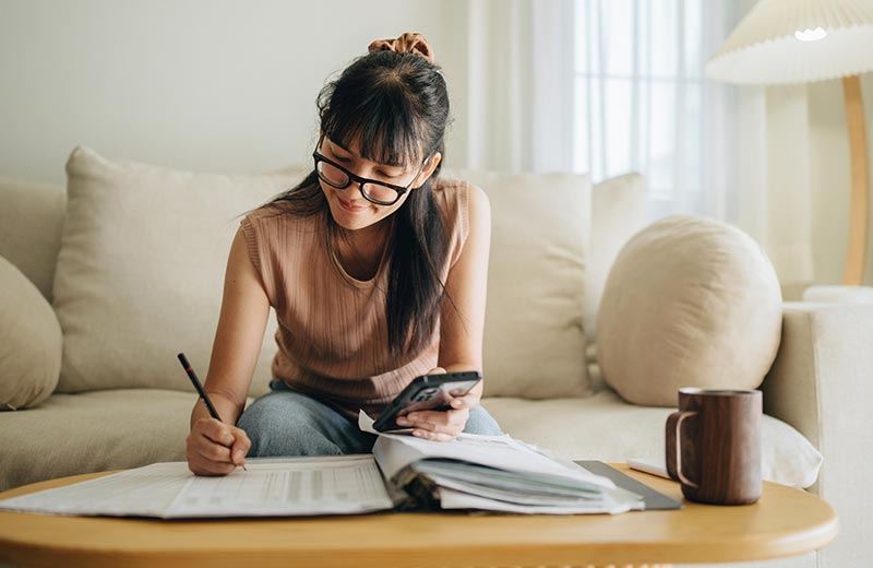 Woman using calculator filling out papers.