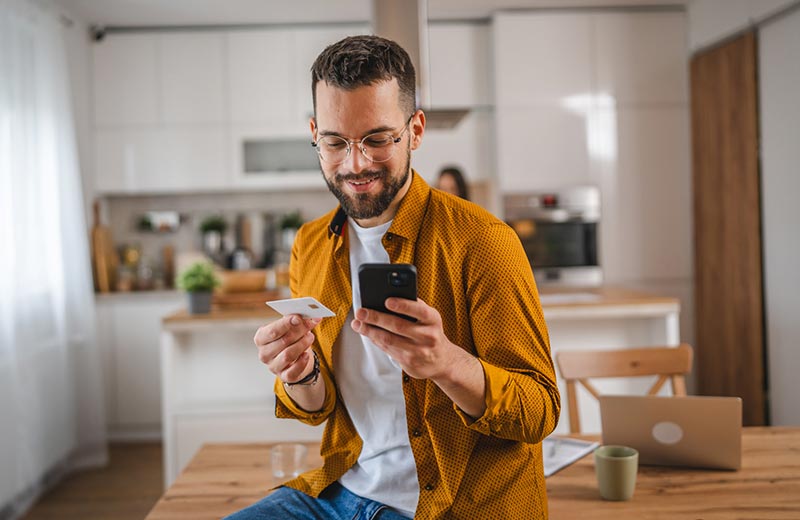 Man with credit card and phone at home.