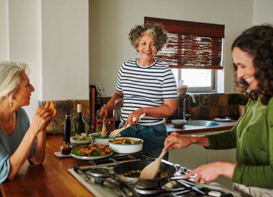 Friends cooking and enjoying a home cooked meal together