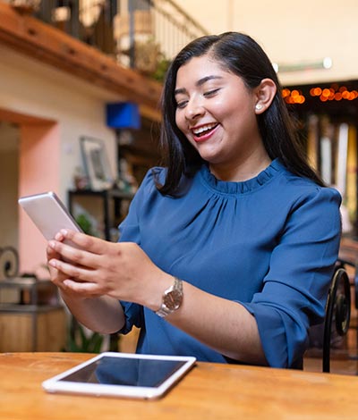 Woman looking at phone with a tablet.